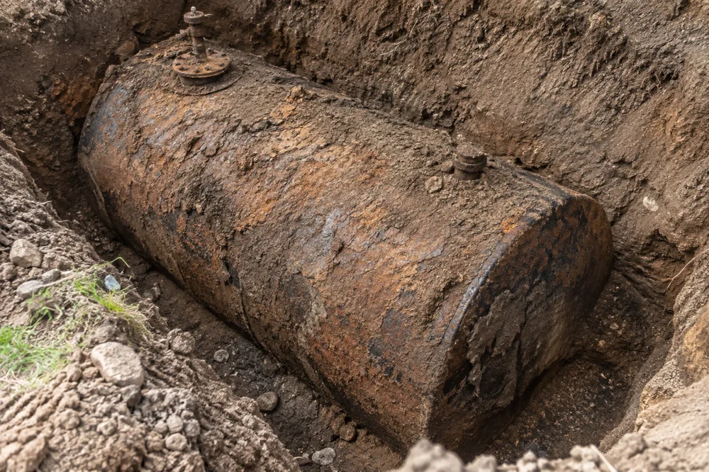 Before: rusted underground oil tank exposed in an excavation